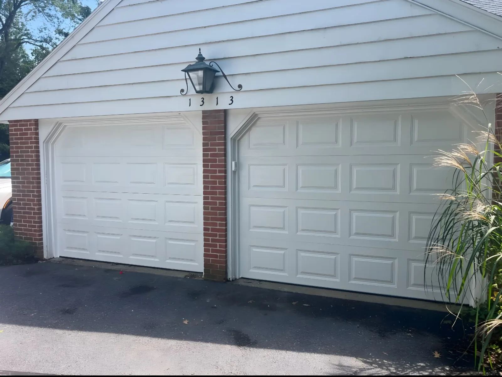 Two white raised-panel garage doors installed side by side on a residential garage