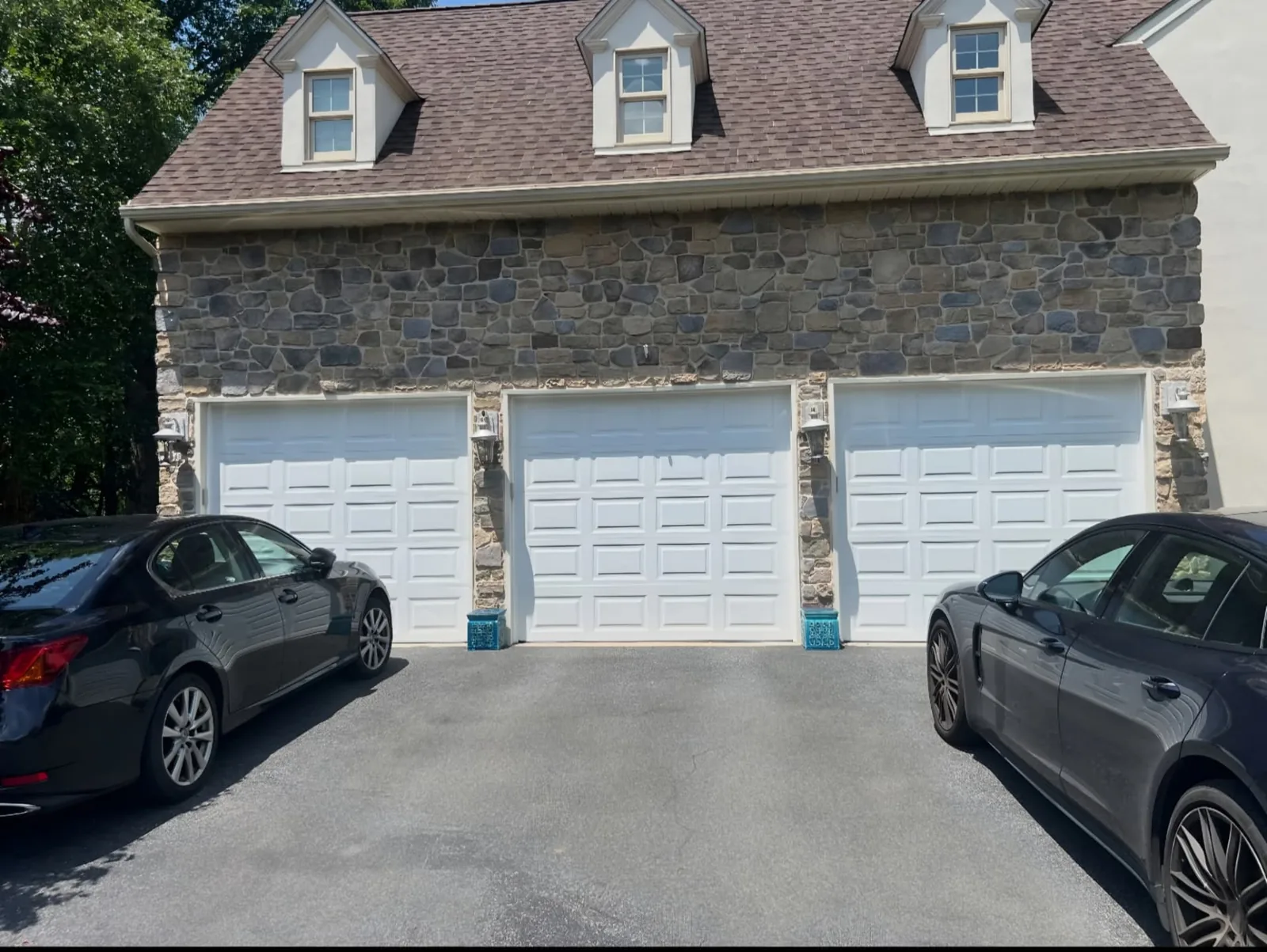 Three matching white raised-panel garage doors on a stone-front three-car garage