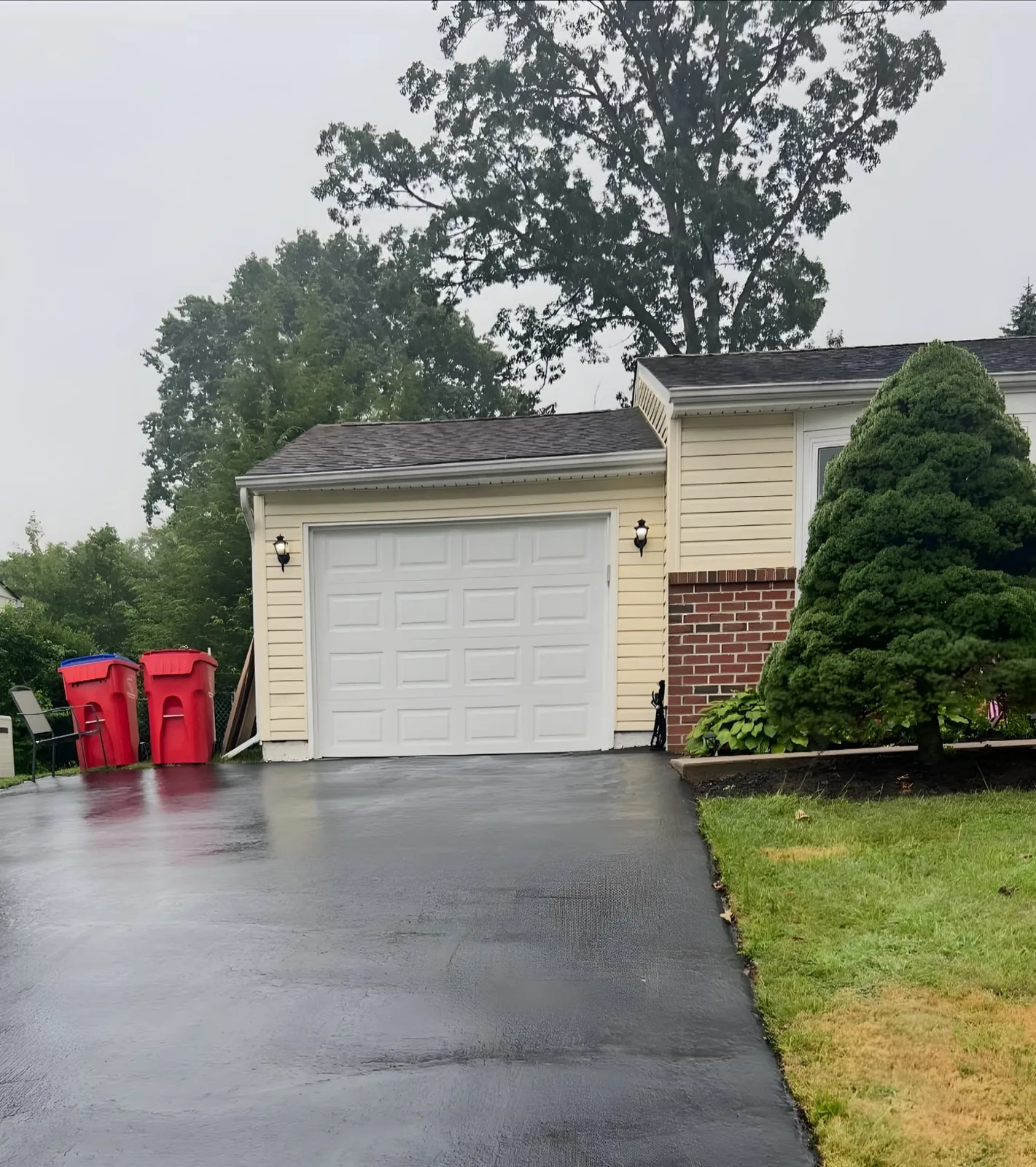 White raised-panel garage door on a yellow-sided home beside a paved driveway