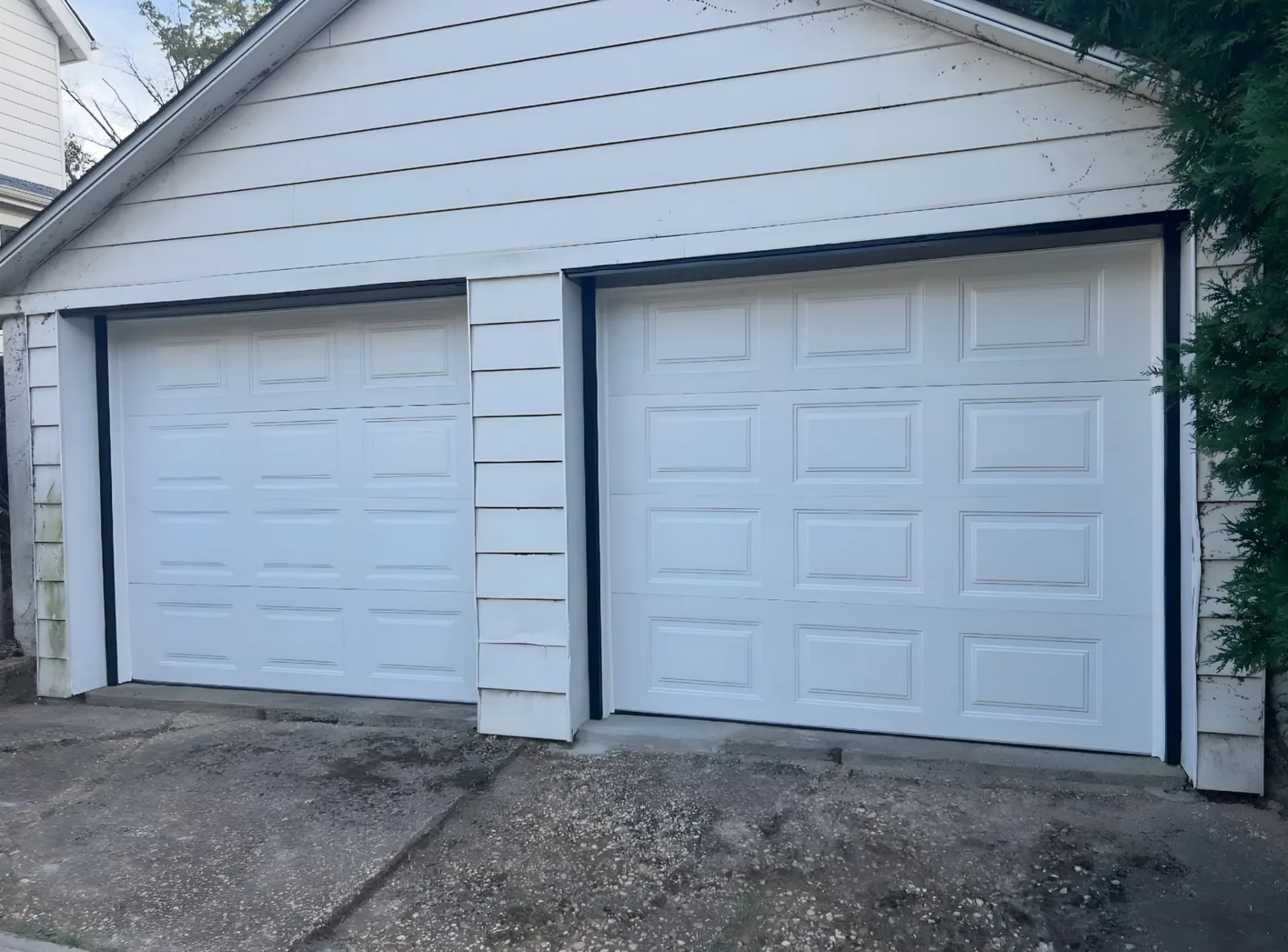 Two white raised-panel garage doors with contrasting dark perimeter trim